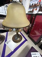 Full view of metal table lamp with frosted glass shade and cabochon accents