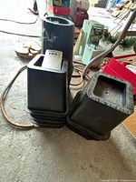 Two nested stacks of square black plastic nursery pots showing overall quantity and condition