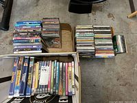 Overall view of stacks of DVD cases and CD jewel cases on floor and in boxes