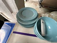 Stack of light blue stoneware dinner plates next to matching bowl