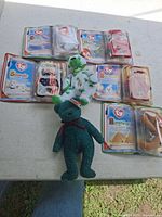 Overview of all seven Ty items: six sealed Teenie Beanie Babies arranged on table plus loose green Holiday bear