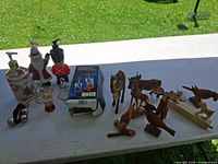 Overview of all items on table: 3 soap dispensers, drinking bird box, glass pieces, wooden animals
