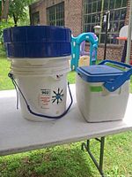 Water system bucket and Coleman cooler on table outdoors