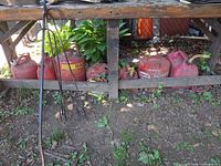 Row of seven red gas cans under wooden bench