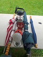 All items laid out: Coleman lantern, red lantern, bulb light on stand, four umbrellas