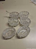six pressed glass salt cellars and metal spoon