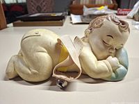 Left side view of rubber sleeping baby bottle holder showing strap and bell
