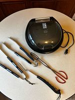 George Foreman grill with five utensils laid out