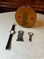 All items displayed: watch, two bottle openers, wood plaque
