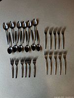 Full set of 28 matching stainless steel cutlery pieces laid out on countertop