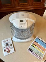 Flavorwave Turbo Oven with glass bowl, rack, lid, manual, chart on countertop