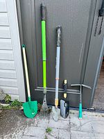 Five garden tools leaning against shed door