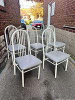 Five white metal chairs with gray vinyl seats, front angle