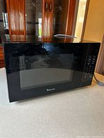 Front view of microwave showing brand logo, viewing window and control panel