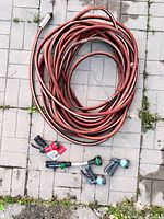 Coiled red rubber hose with four nozzle attachments laid out