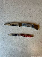 Two pocket knives open showing blade and handles
