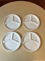 Four white sectioned Corelle plates top view
