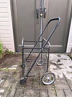 Side view of folding wire shopping cart showing wheels, basket and handle