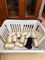 Basket containing multiple ivory silk thread spools plus one black spool