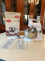 stand mixer with bowl, attachments, manual and box on countertop