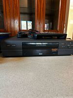 Front view of RCA VCR with remote and cable on top
