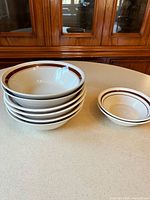 Stack of six large bowls beside two small bowls showing size difference and brown rim detail