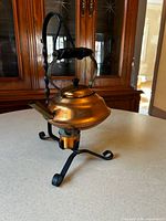 Side view of copper kettle on wrought iron stand with warmer