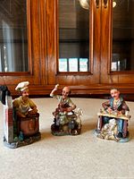 Three ceramic figurines—chef, cobbler, woman with lamb—front view