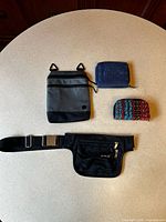 All four items laid out: travel pouch, blue wallet, beaded purse, fanny pack