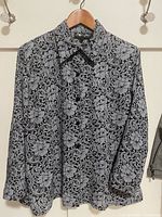 Front view of black and grey floral sparkle blouse on hanger