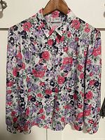 Front view of floral blouse on hanger showing overall design