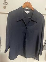 Front view of navy blue blouse on hanger