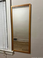 Full view of rectangular mirror with oak wood frame mounted on wall