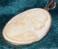 Front angled view of oval shell cameo pendant in 10K gold frame