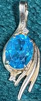 Front view of gold pendant with blue topaz and accent stones