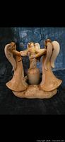 Front view of ceramic angel candle holder showing three angels and central candle cup