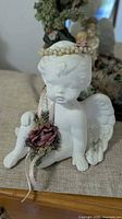 Front view of seated white cherub figurine with pearl halo and floral accents