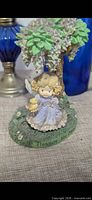 Front view of Precious Moments angel figurine under tree