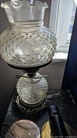 Full view of clear hobnail glass oil lamp, showing shade, font, and ornate base