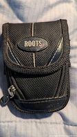 Front view of black Roots nylon camera pouch