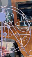 side view of pastel pink wire Ferris wheel cupcake holder showing several hanging cupcake rings