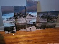 Five shrink-wrapped landscape canvas panels leaning against wall