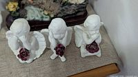 Three kneeling angel figurines with roses front view