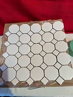 stack of white octagon-dot mosaic tile sheets still in plastic wrap