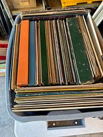 Grey plastic tote filled with upright 12-inch vinyl record albums in assorted colored sleeves