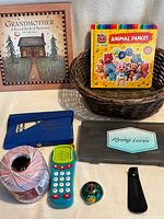 Lot overview showing books, basket, crochet thread, toy phone, plastic cases and small items
