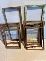 Stacked group of eleven empty gold-tone picture frames, assorted profiles and sizes