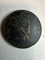 Front view of medal showing portrait, inscription, drilling, corrosion