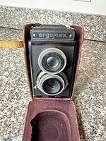 Front view of Argoflex camera in open leather case showing dual lenses and nameplate