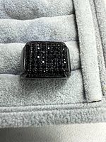 Top view of ring showing rectangular face fully set with rows of black CZ stones